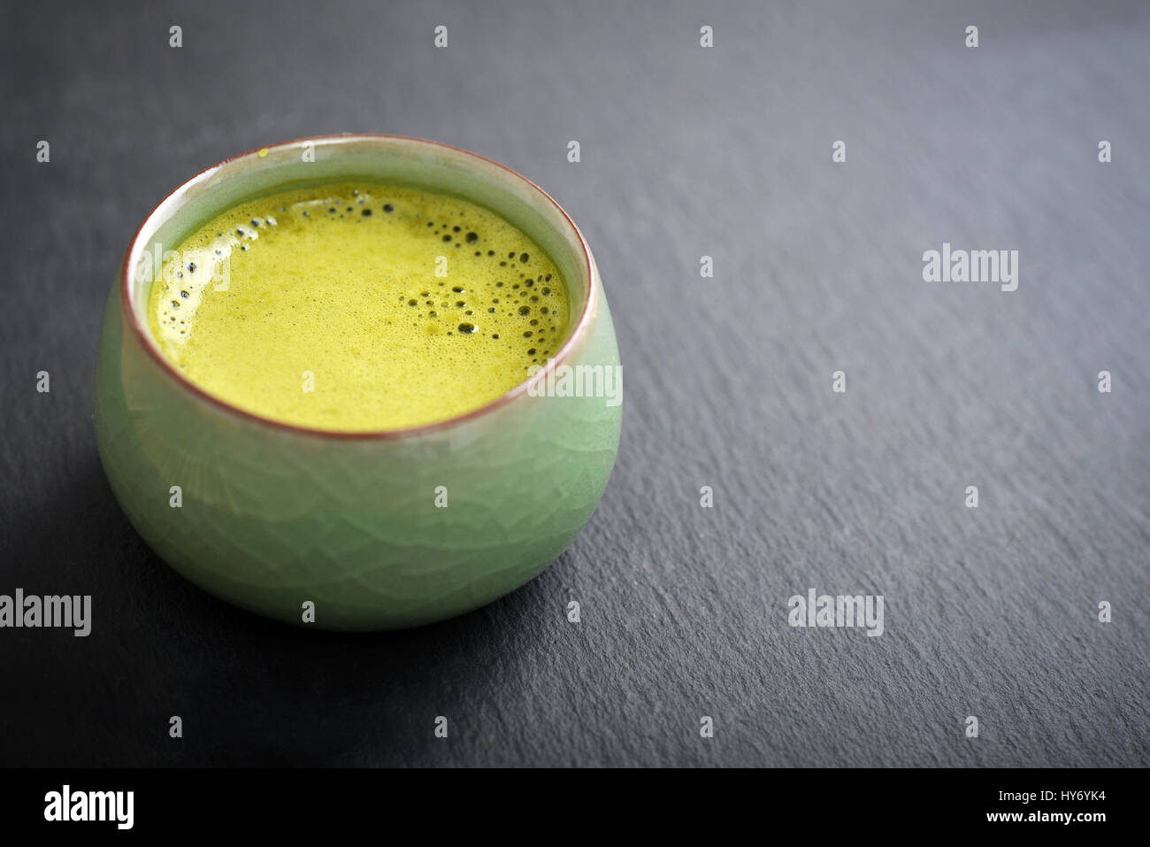 Organic Green Matcha Tea in a small cup over slate background Stock Photo