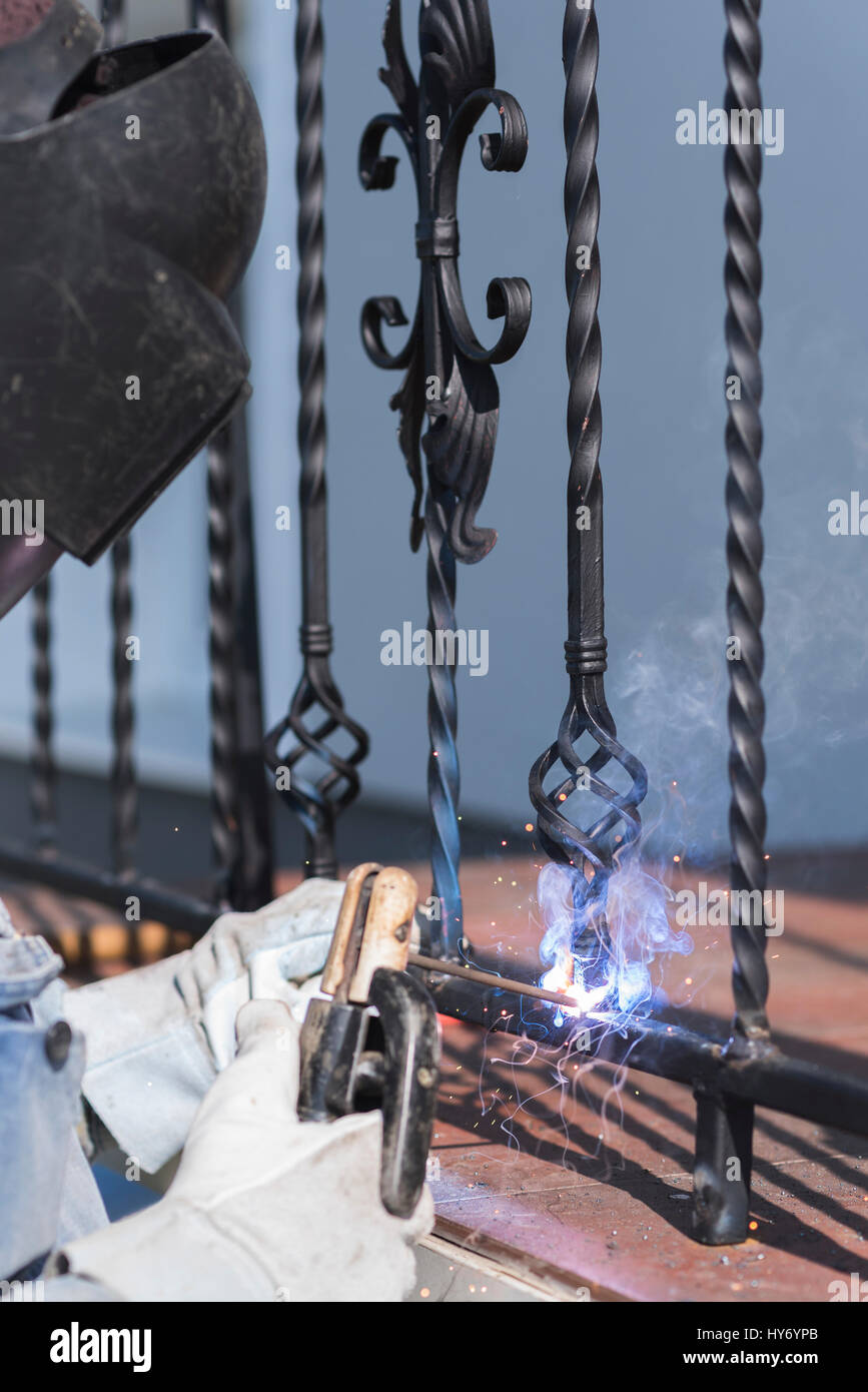 A worker welding metal handrails on the stairs. Wrought iron railings