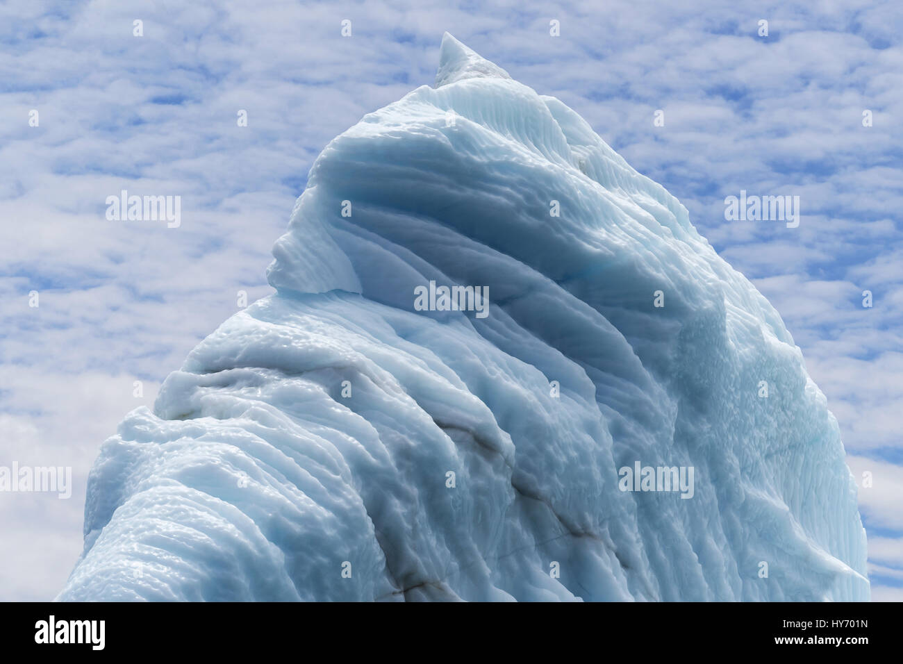 Convoluted blue ice and cloudy blue sky, Cuckold Cove, Bonavista Peninsula, Newfoundland Stock Photo