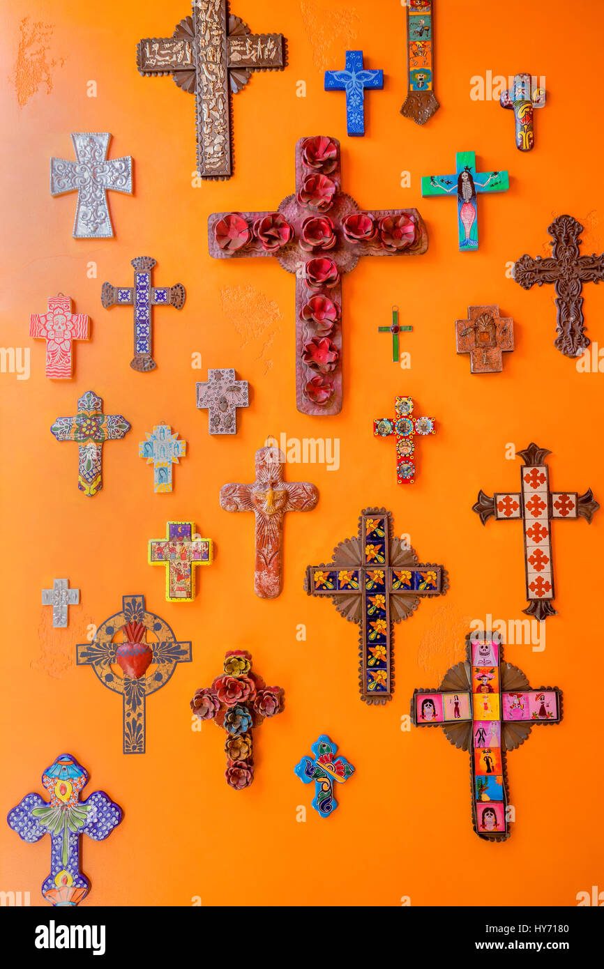 Various crosses hanging on an orange wall Stock Photo