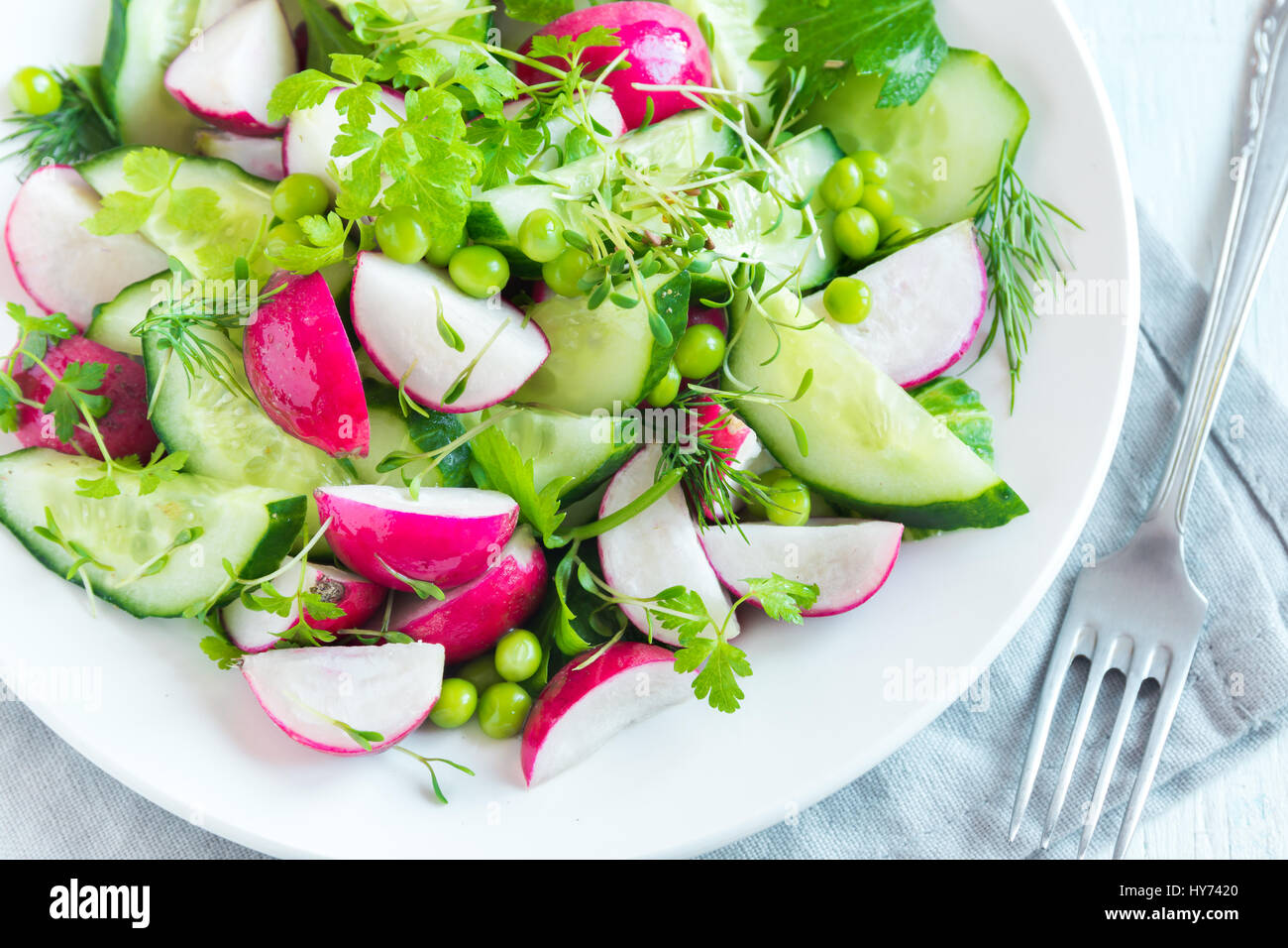 Healthy spring vegetables salad with radish, cucumber, green peas and sprouts, diet, vegetarian, vegan, organic, green food, spring detox snack. Stock Photo