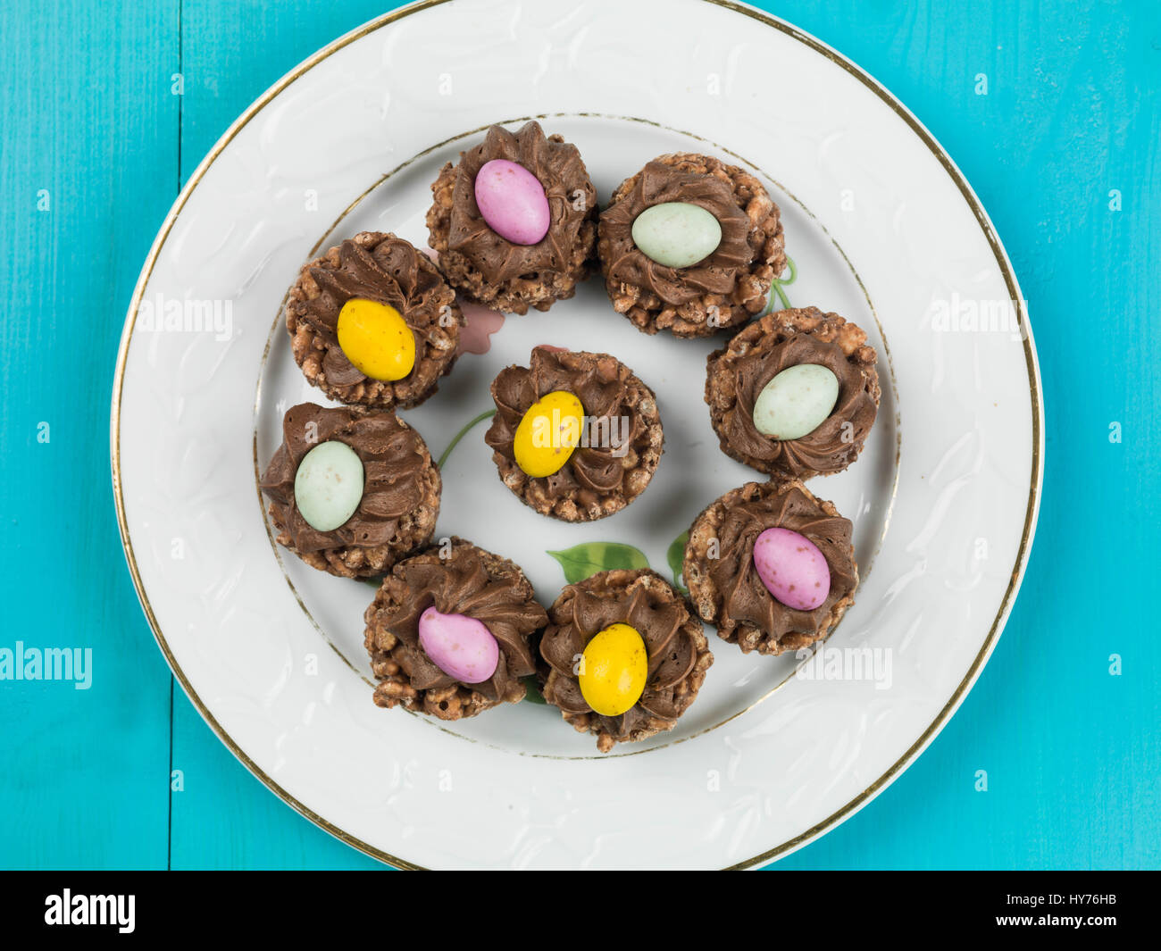 Easter Chocolate Crispy Cereal Nests With Mini Easter Eggs Against a Blue Background Stock Photo