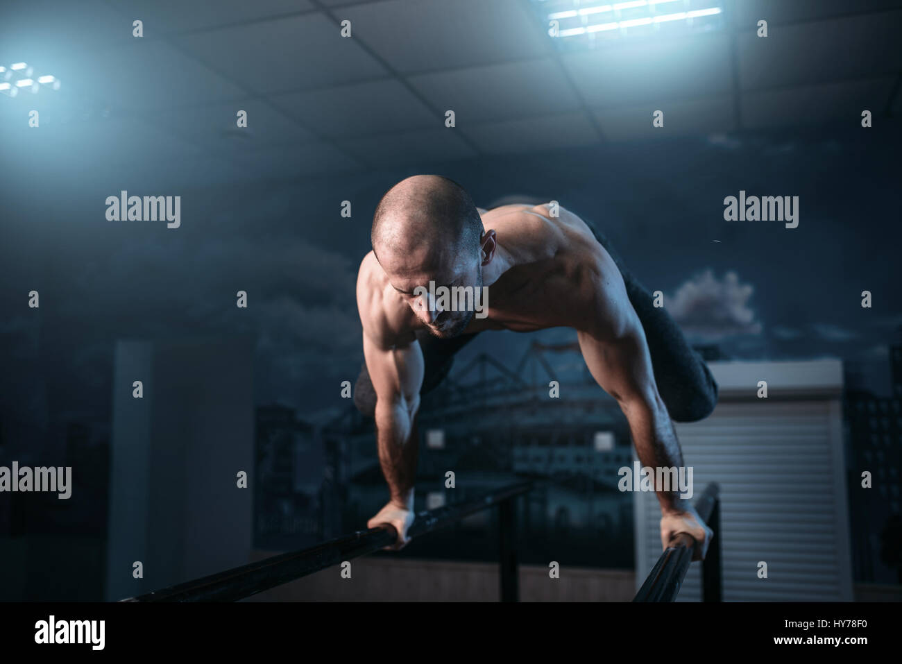 Muscle athlete makes horizontal balance exercises on gymnastic bars in