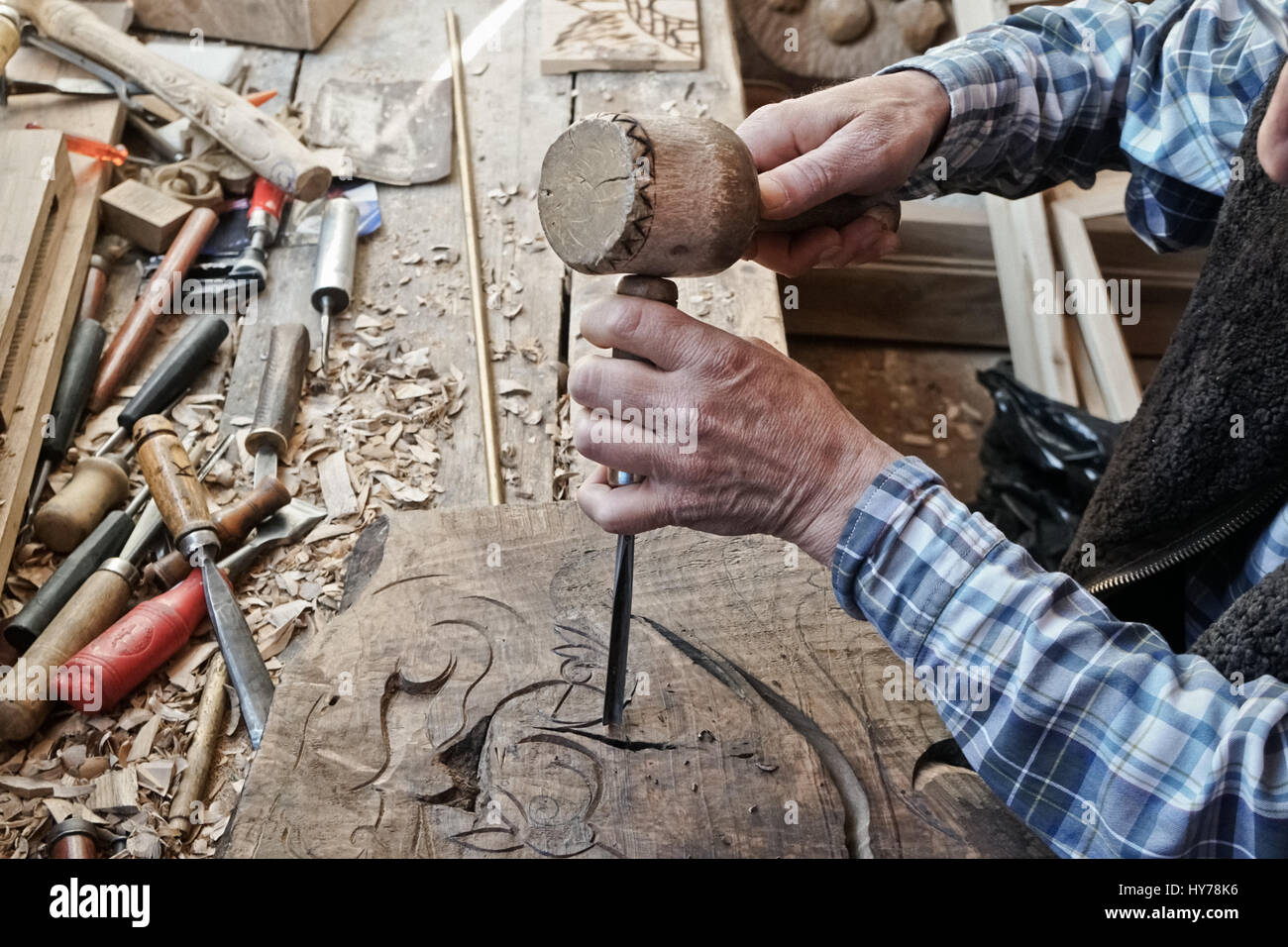 Wood carving. Carver with chisel and hammer. A skillful craftsman