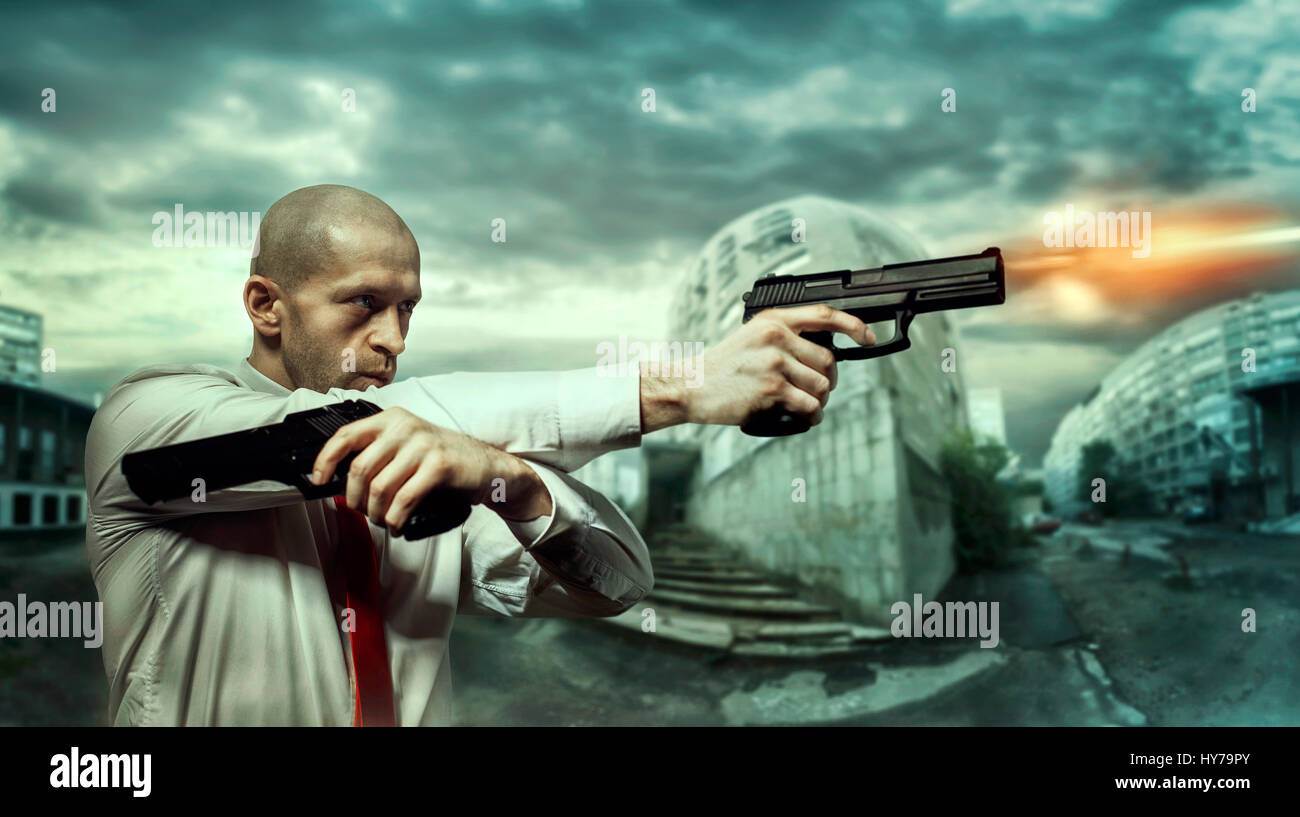 Serious hired killer in red tie shoot a pistols with two hands, night urban landscape on background. Contract assassin shooting action wallpaper or po Stock Photo