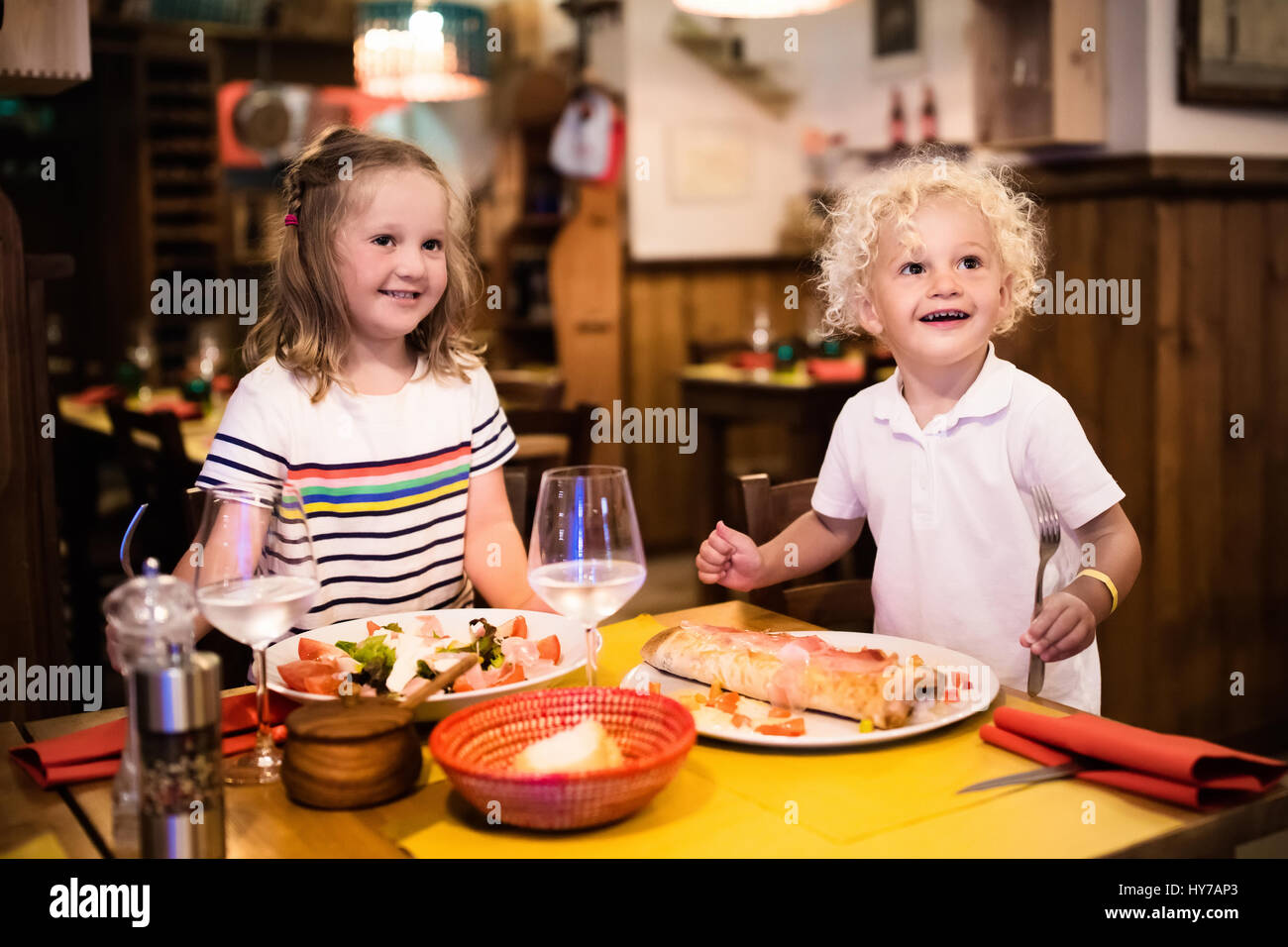 Kids eat pizza, pasta and salad in traditional restaurant. Eating out with  children. Boy and girl having dinner in pizzeria in Italy on vacation in E  Stock Photo - Alamy