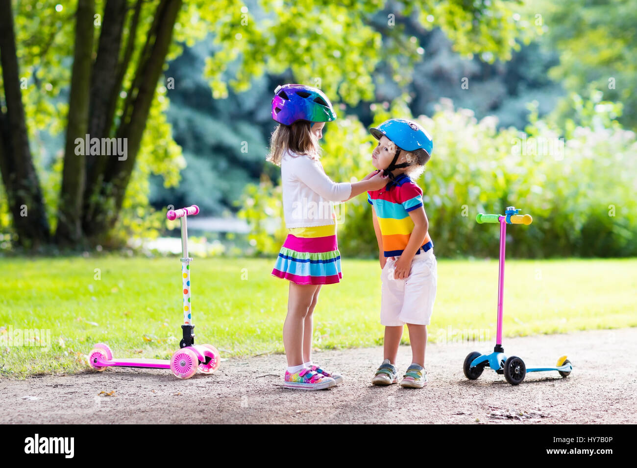 Children learn to ride scooter in a park on summer day. Preschooler