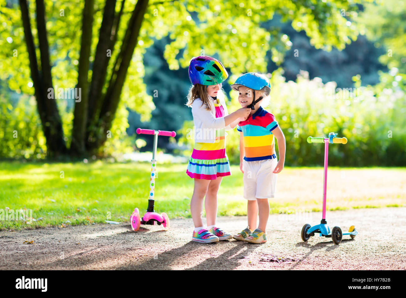 Children learn to ride scooter in a park on summer day. Preschooler