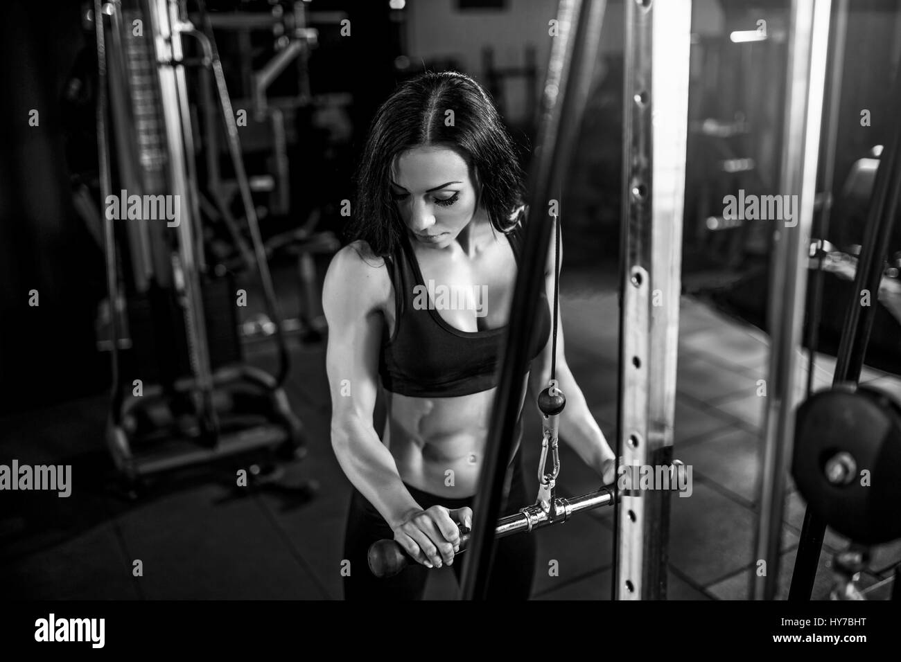 woman flexing muscles on cable machine in gym. exercise on triceps Stock Photo