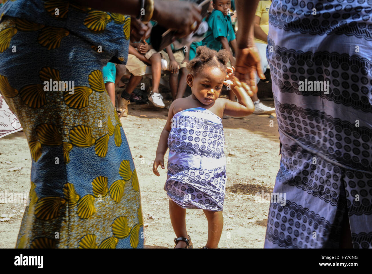 A baby girl stands in the middle of a dance circle during a festival in rural Ghana. Stock Photo