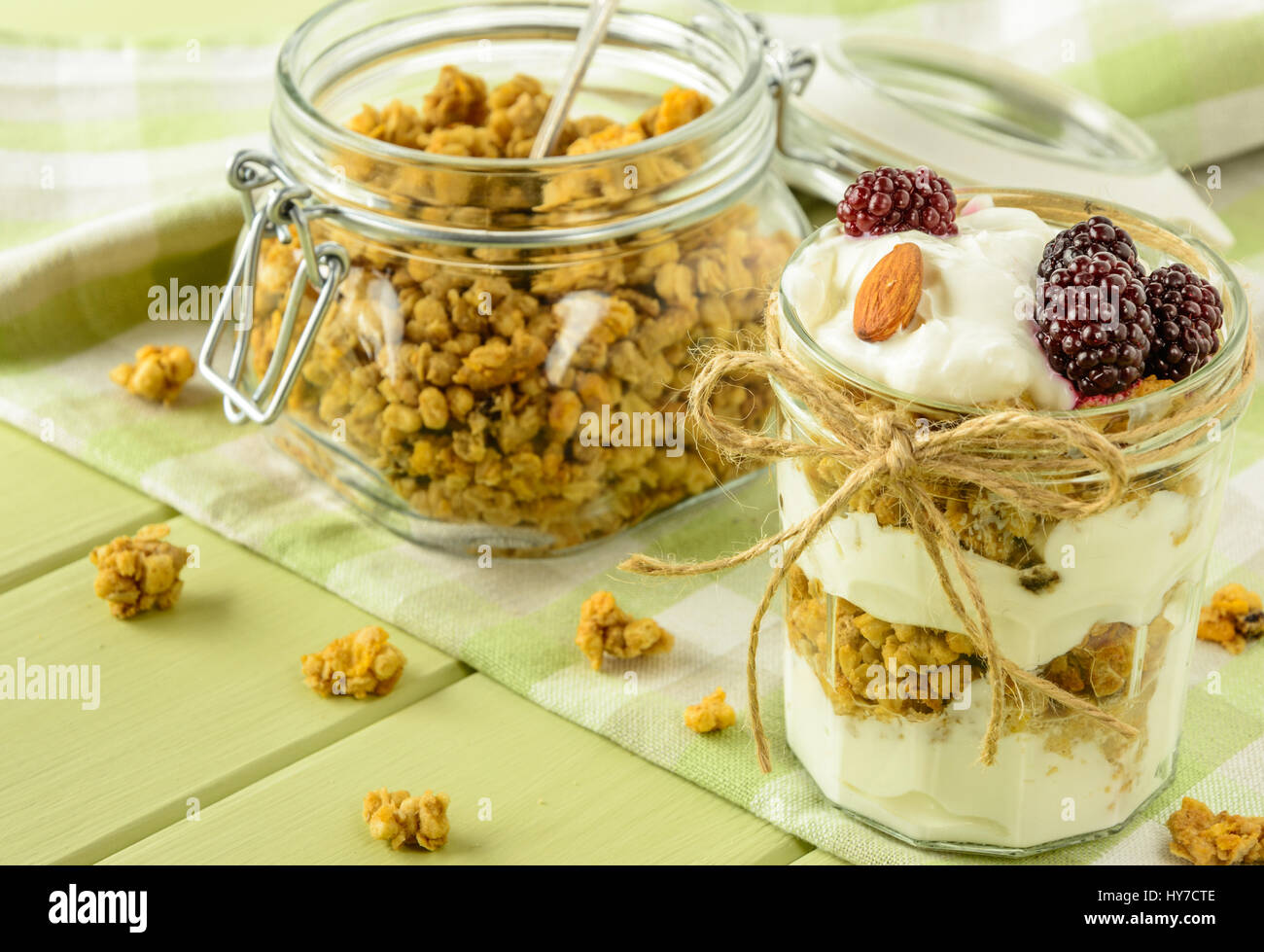 Healthy breakfast ingredients. Homemade granola with yoghurt in open glass jar. The food is rich in useful carbohydrates, vitamins and nutrients that  Stock Photo
