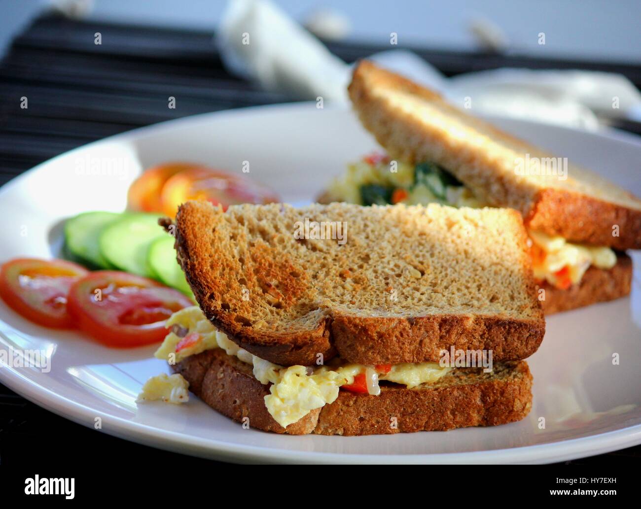 Satisfy your appetite with an egg sandwich served with tomatoes and cucumbers. Stock Photo