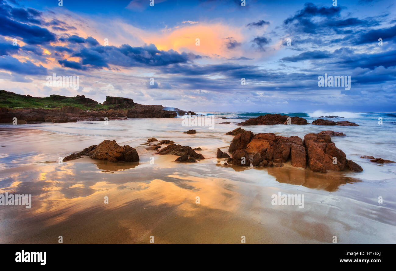Sandy beach and sandstone boulders at sunrise near Stockton beach in NSW, Australia. Eastern Pacific coast. Stock Photo