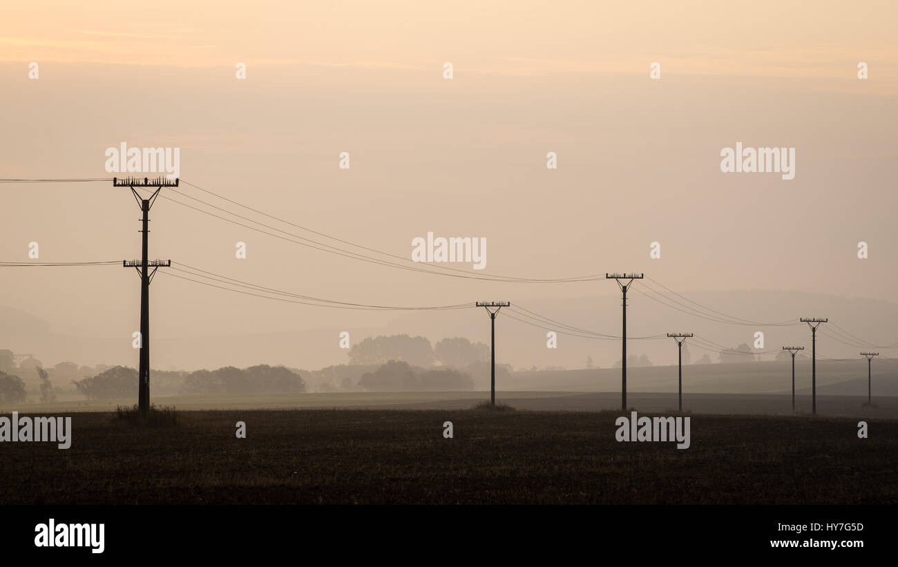 sunset over the fields in fog in summer with electricity poles Stock ...
