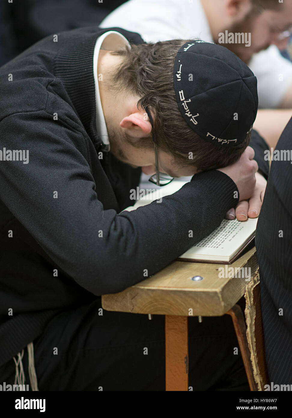 An unidentified religious Jewish boy studying alone from a Hebrew book in a synagogue in Brooklyn, New York. Stock Photo