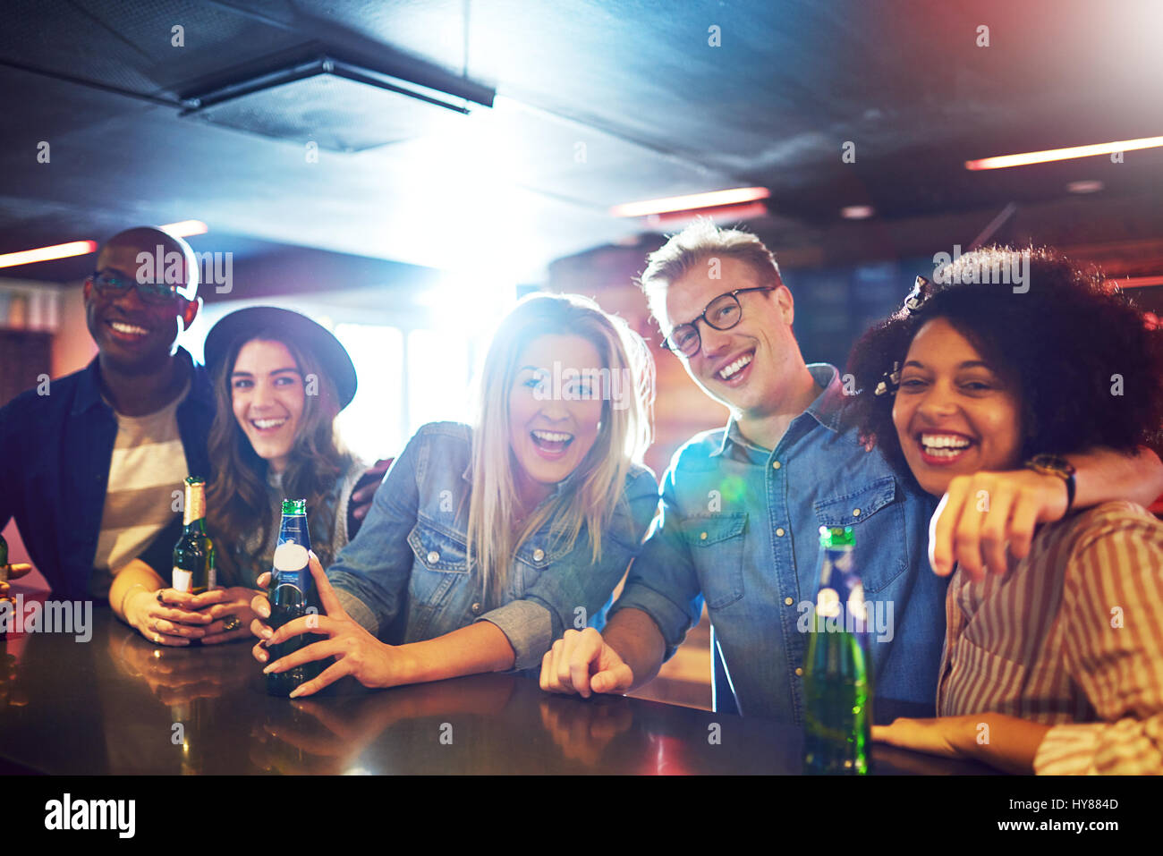 Horizontal shot of happy group of friends in the bar drinking the beer and looking at camera. Stock Photo