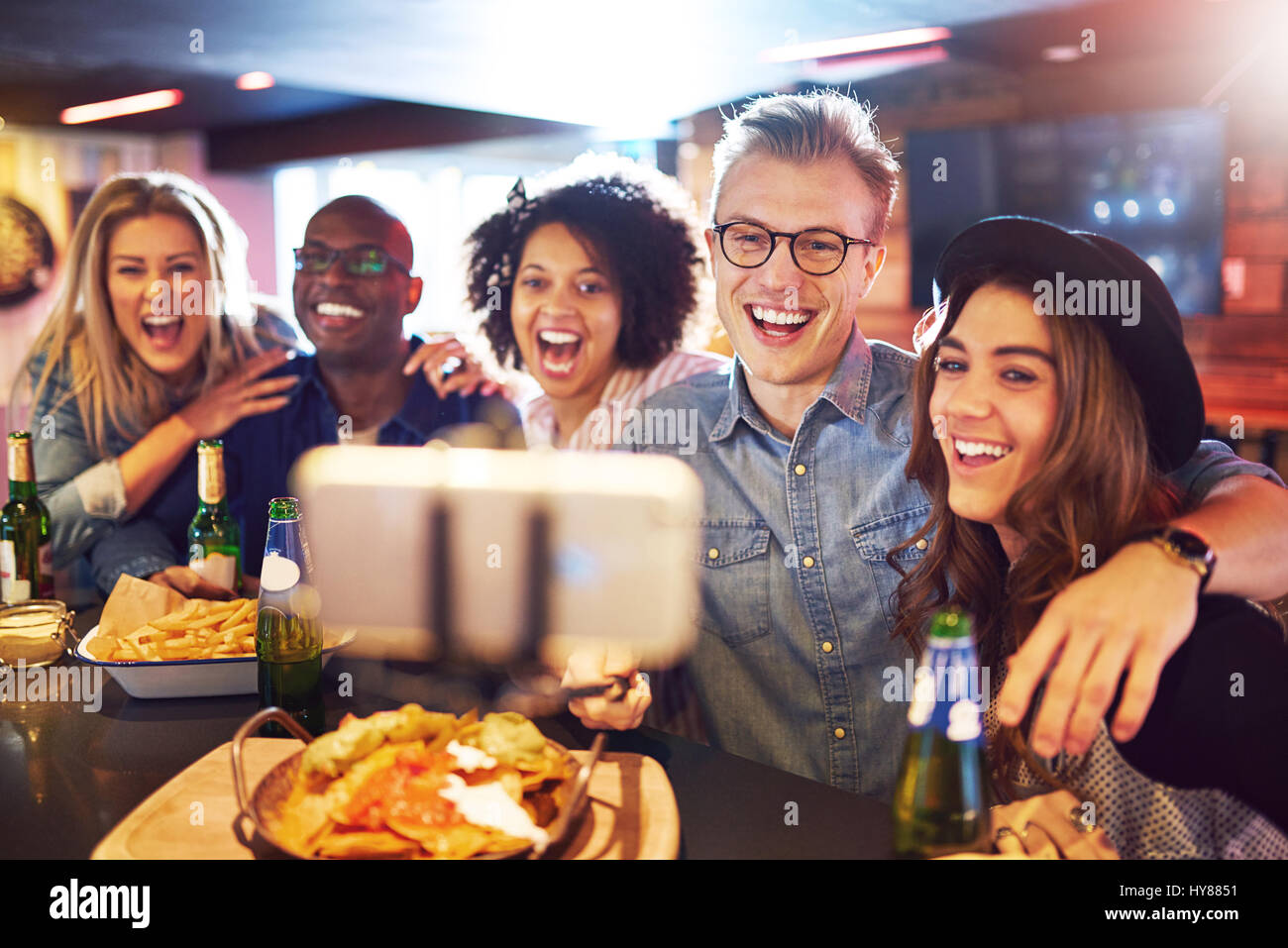 A group of best friends smiling and laughing while taking a selfie in the bar. Stock Photo