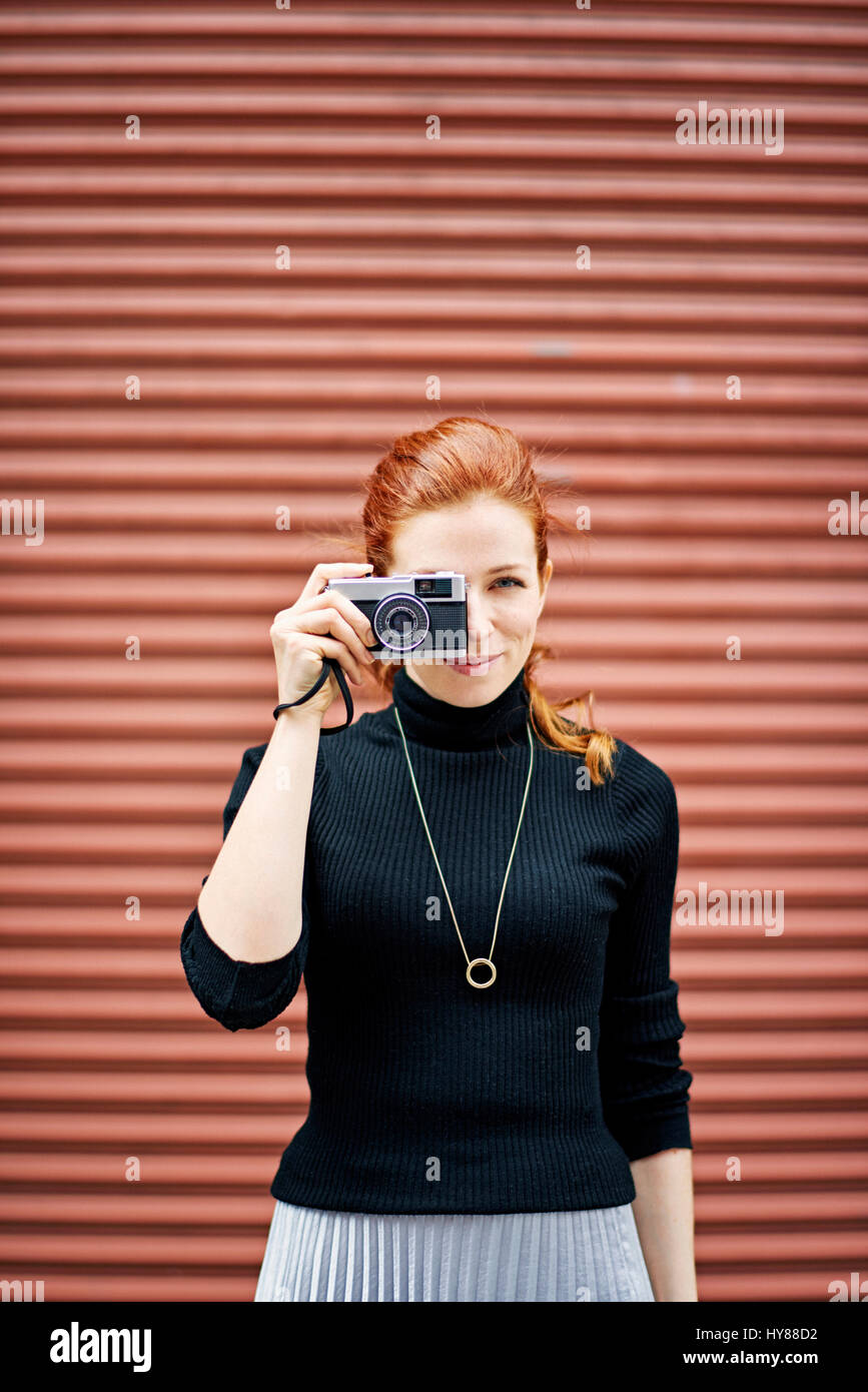 Young fashionable women with classic camera in front of garage door in New York city Stock Photo