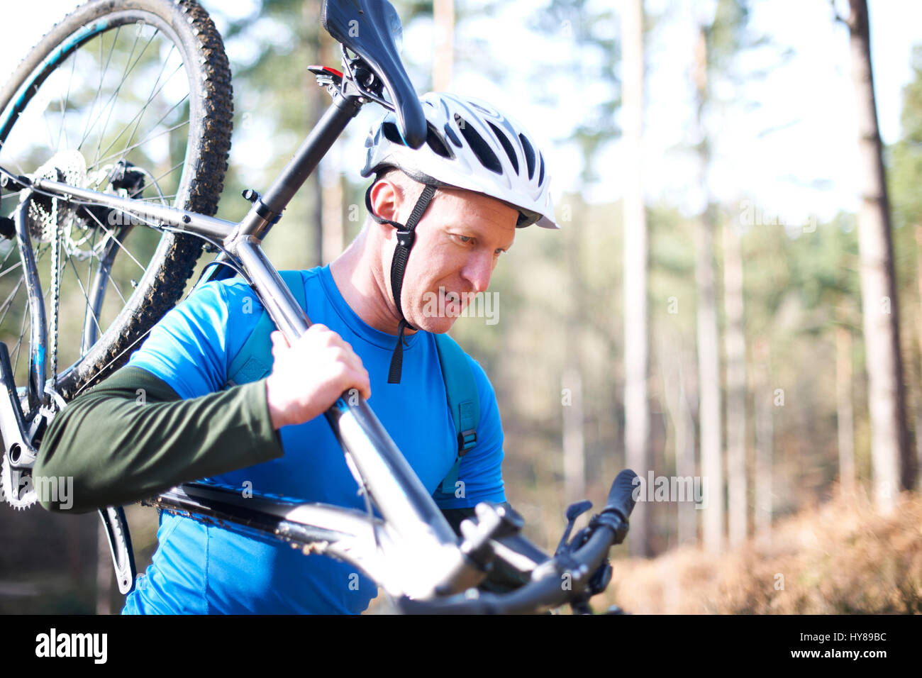 A man carries his mountain bike in the woods Stock Photo
