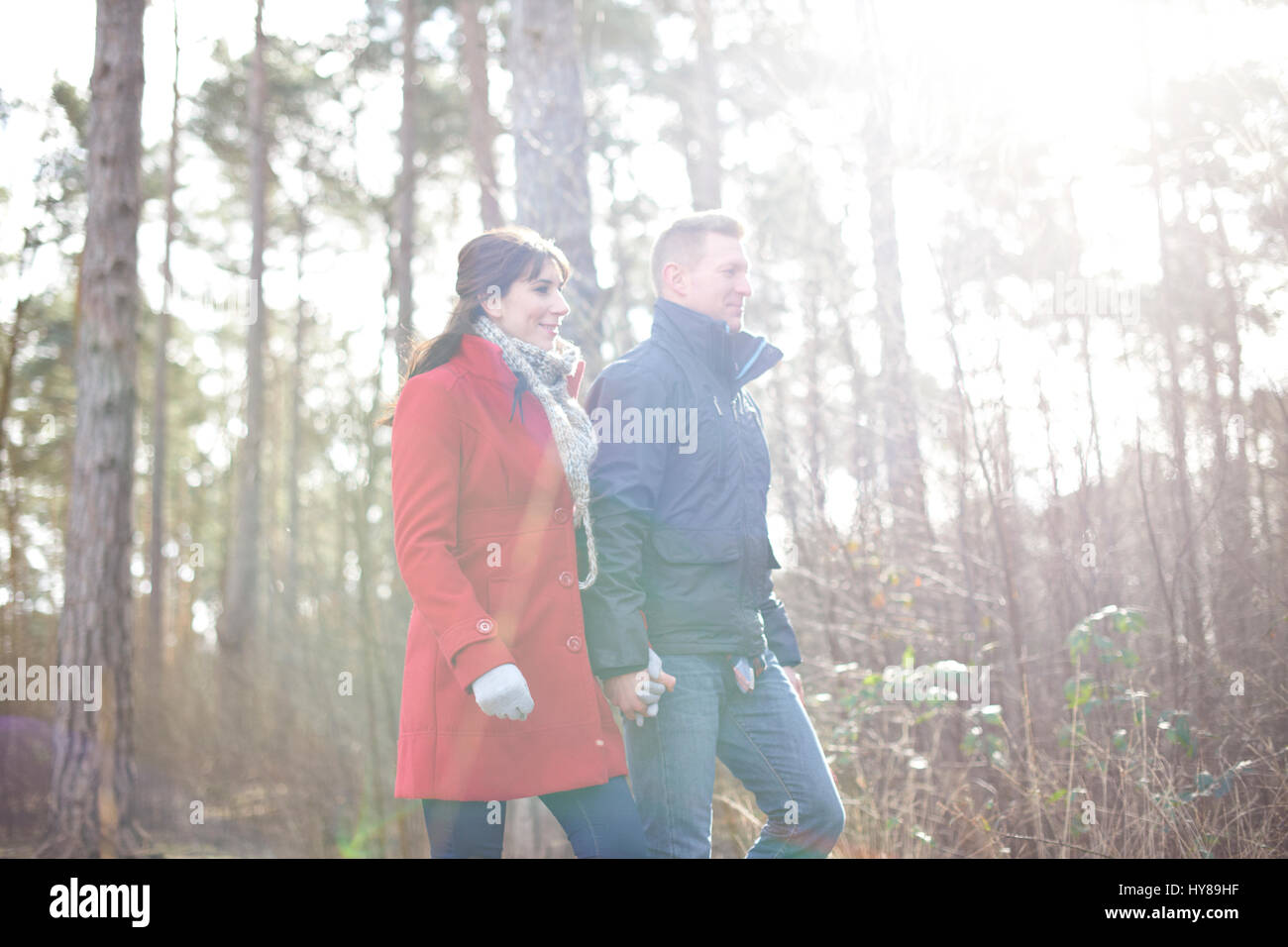 A young couple walk hand in hand in the woods Stock Photo