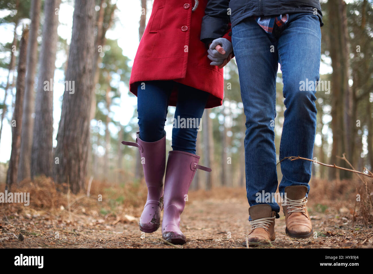A young couple walk hand in hand in the woods Stock Photo