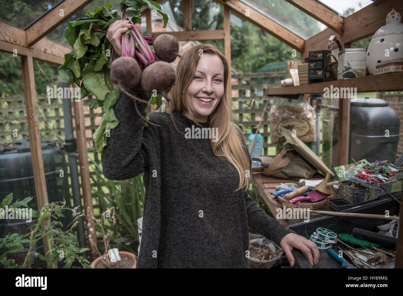 A young female gardener works in her greenhouse Stock Photo - Alamy