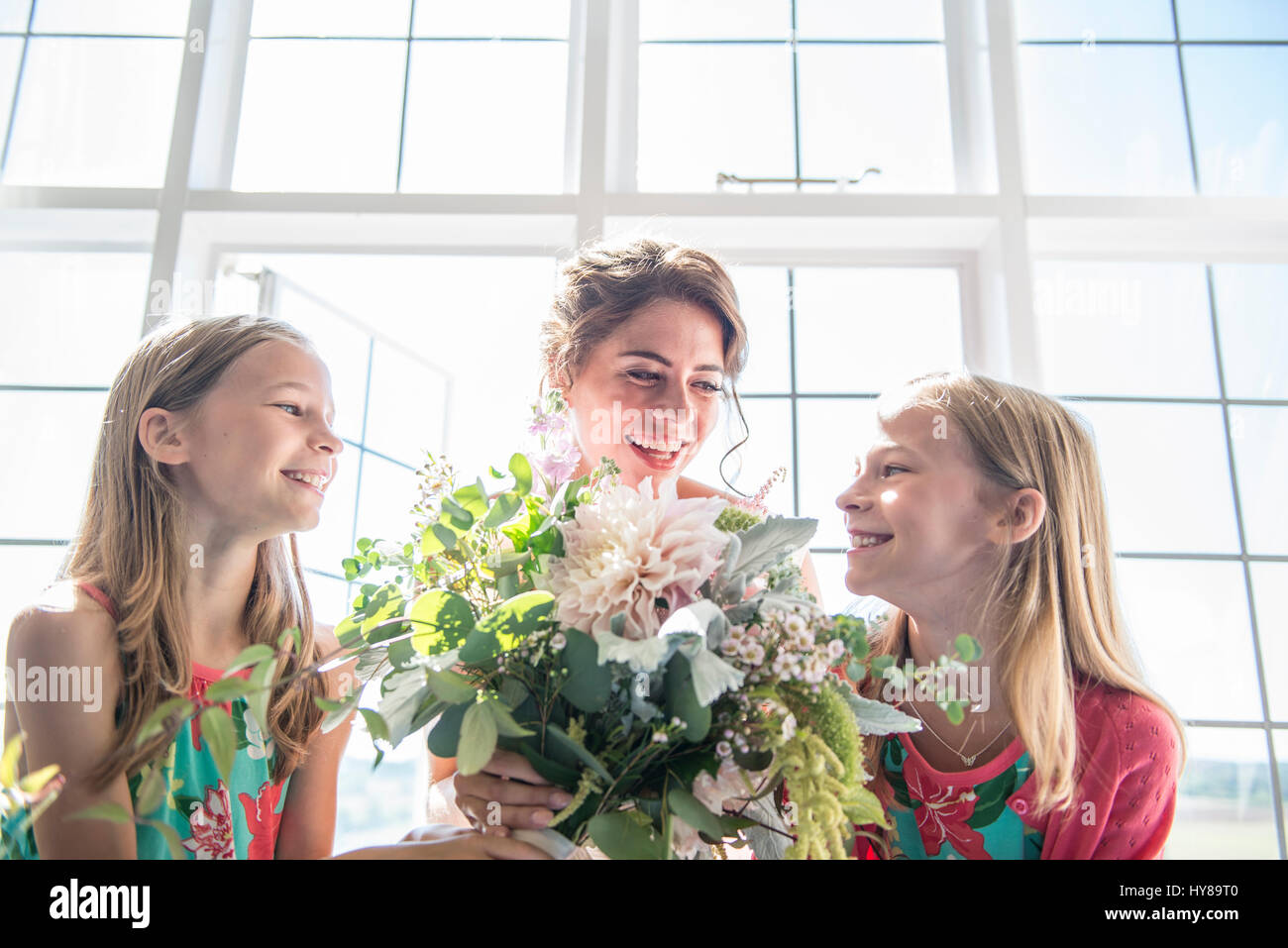 A bride with her twin bridesmaids holding a bouquet of flowers prior to her wedding Stock Photo