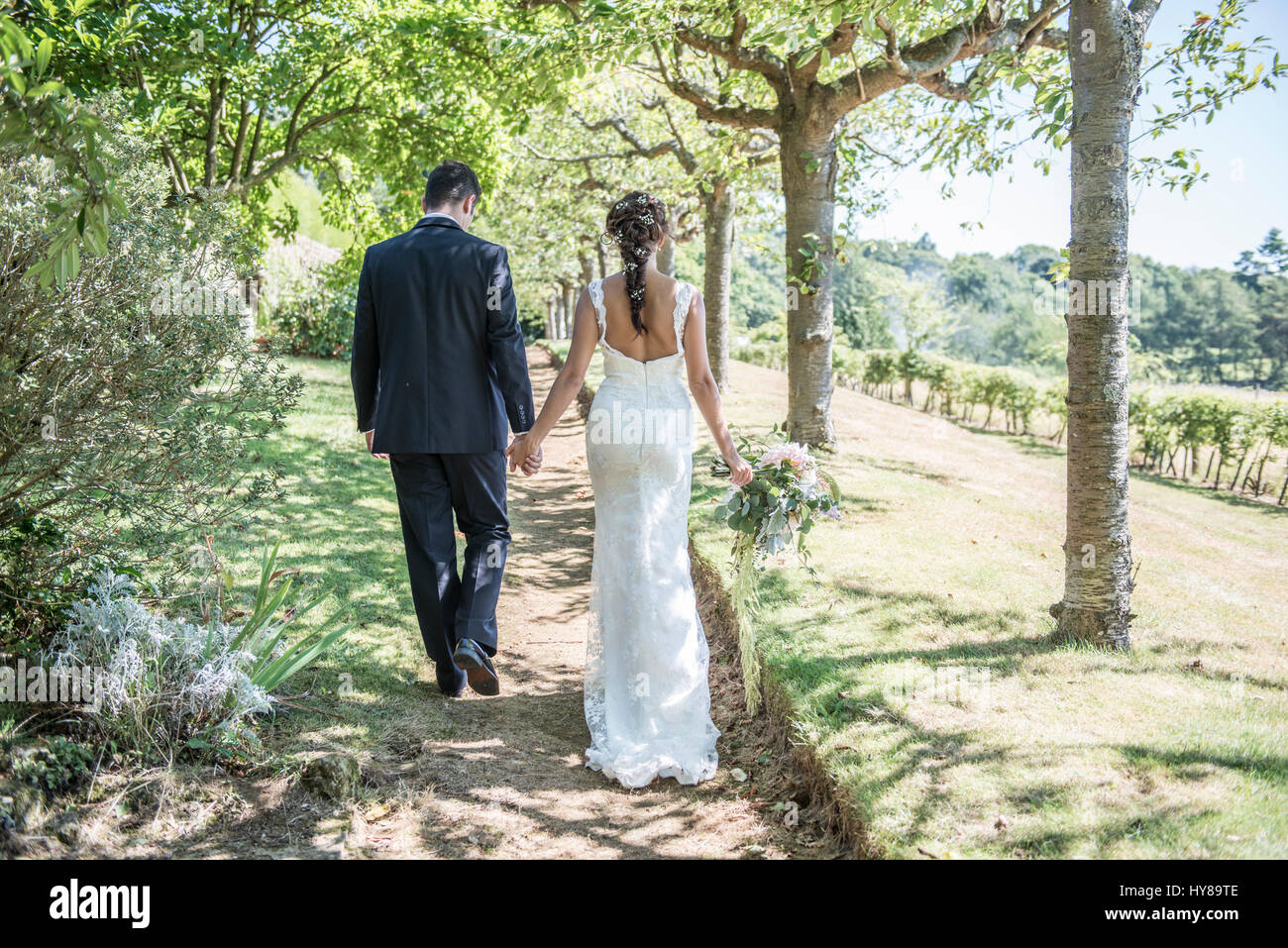 A bride and groom walk along hand in hand on their wedding day Stock ...