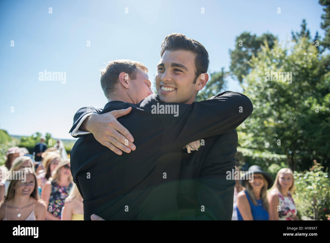 A groom and best man share a hug prior to the wedding service Stock Photo