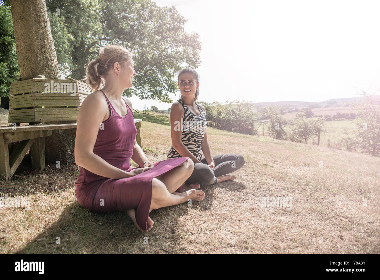 Two female friends sit and practice yoga outside Stock Photo