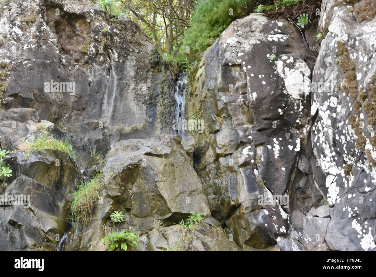 Tiny artificial waterfall between rocks and cliffs Stock Photo