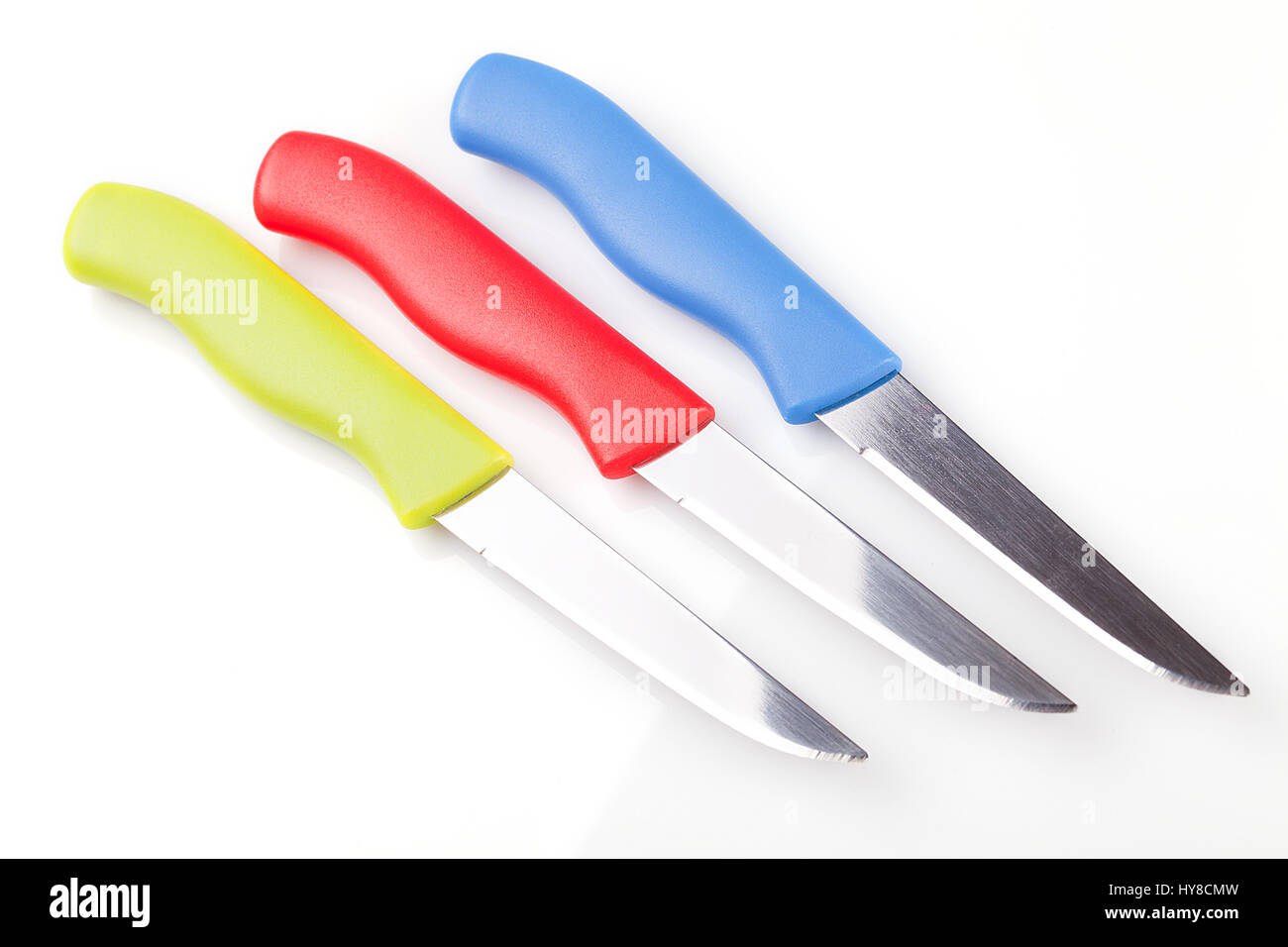 Set of colorful kitchen knives on a white surface. Kitchen tools isolated on white background. Stock Photo