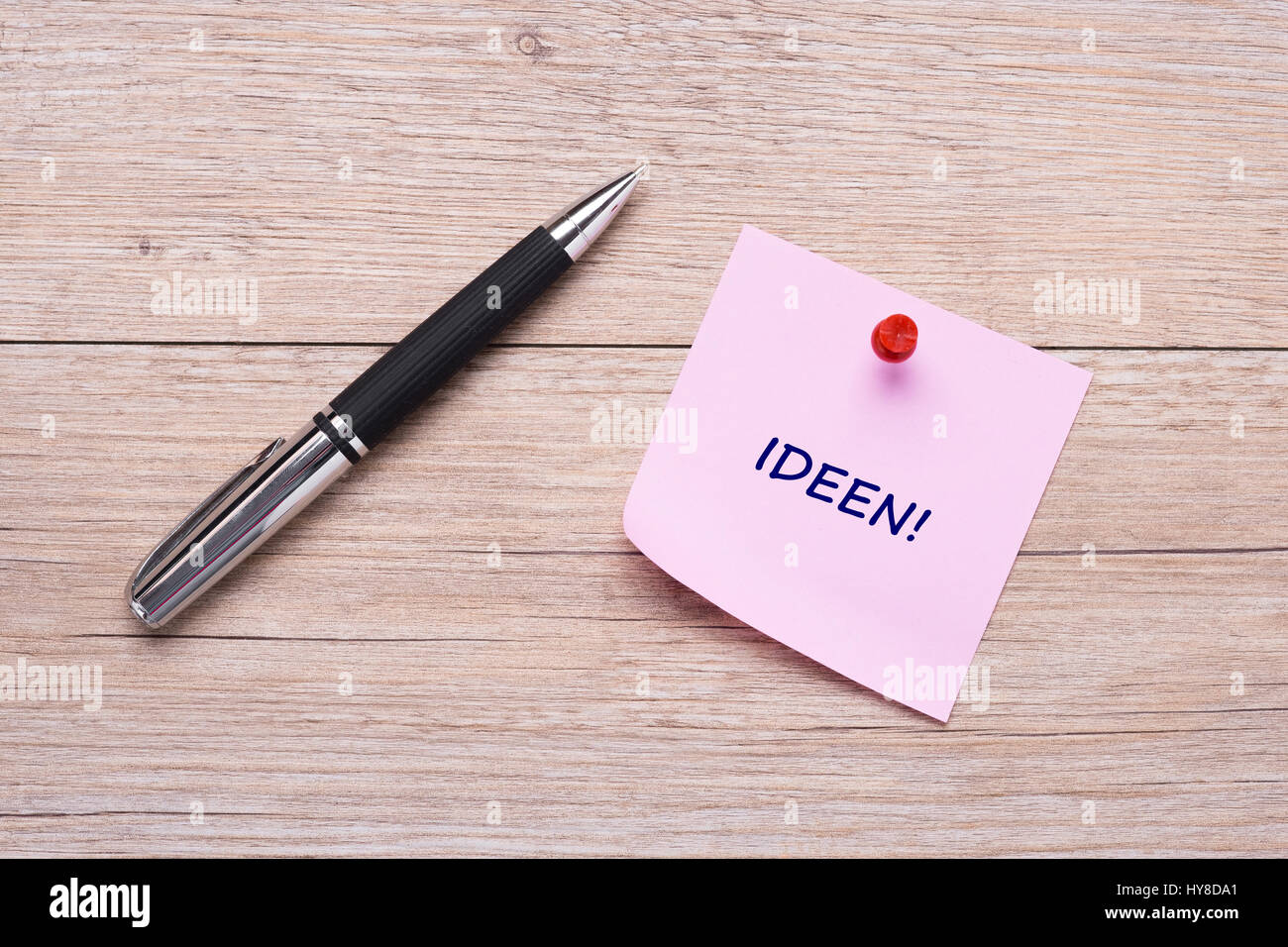 German word 'Ideen' on pink sticky note with pen on wood Stock Photo