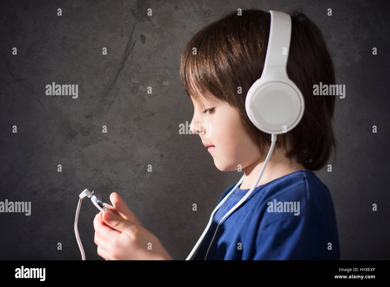 Cute boy with phone and head phones, listening music, indoors, studio shot Stock Photo