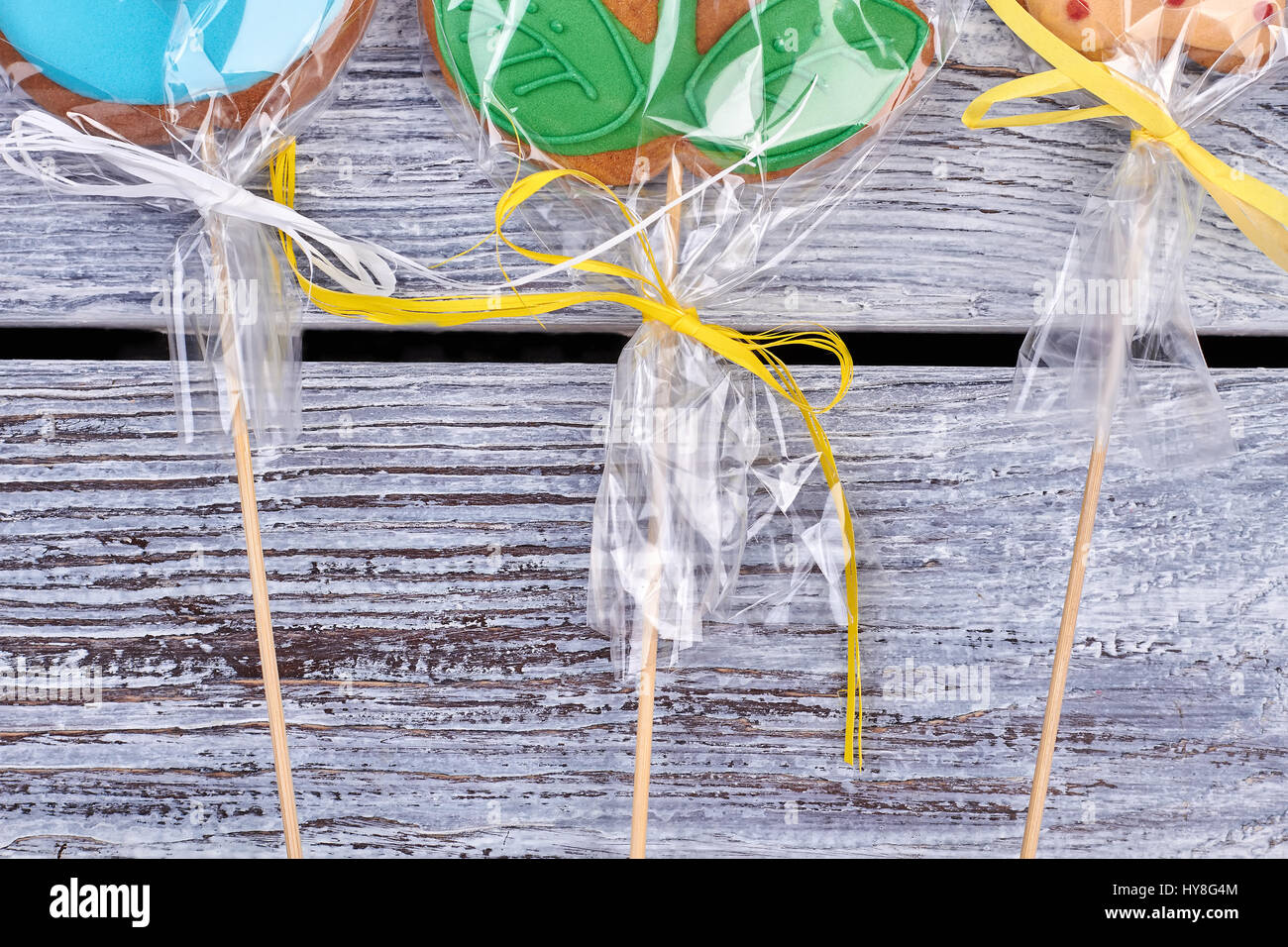 Cookies wrapped in plastic. Biscuits with bows on wood. Birthday party