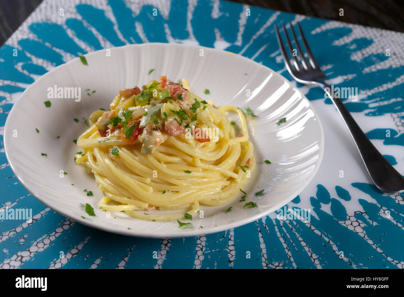 Vegetarian Carbonara - Zucchini (Courgette) and egg spaghetti pasta - Veggie italian recipe served with fork on white and light blue placemat Stock Photo