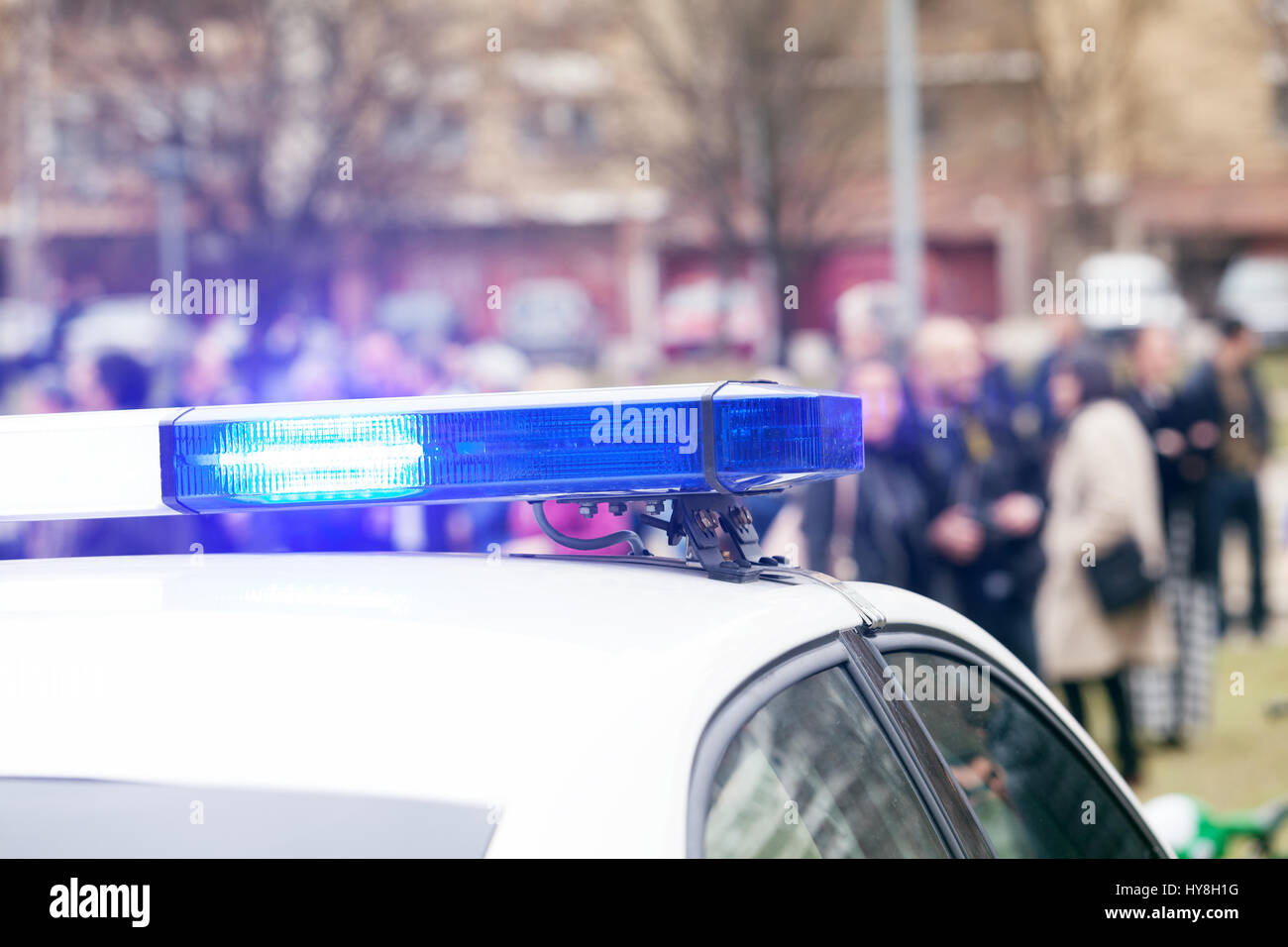Police car lights flashing, with crowd out of focus in background Stock