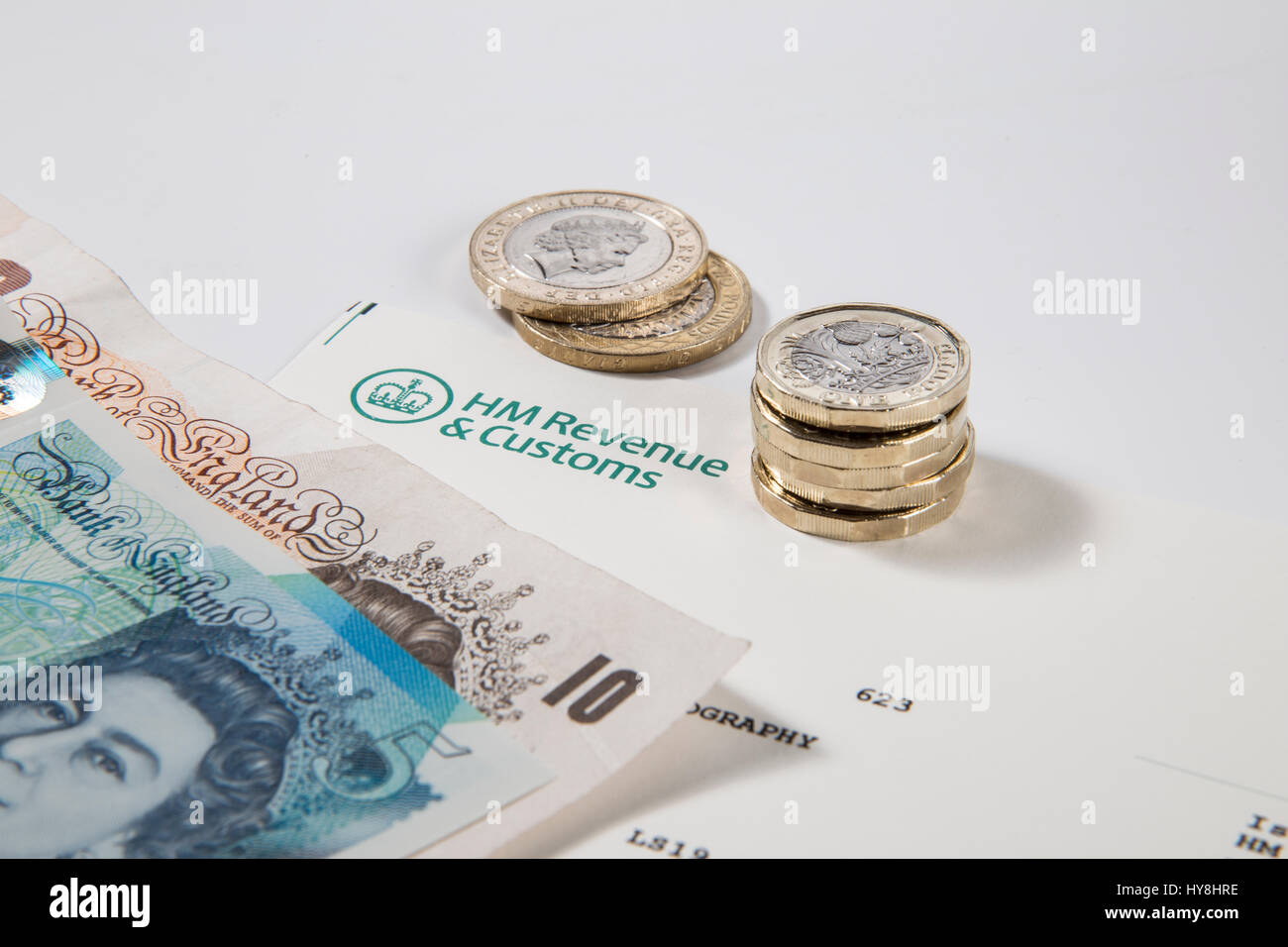 New £1 pound coins, £2 pound coins and £5 pound notes on an HM Revenues & Customs document Stock Photo
