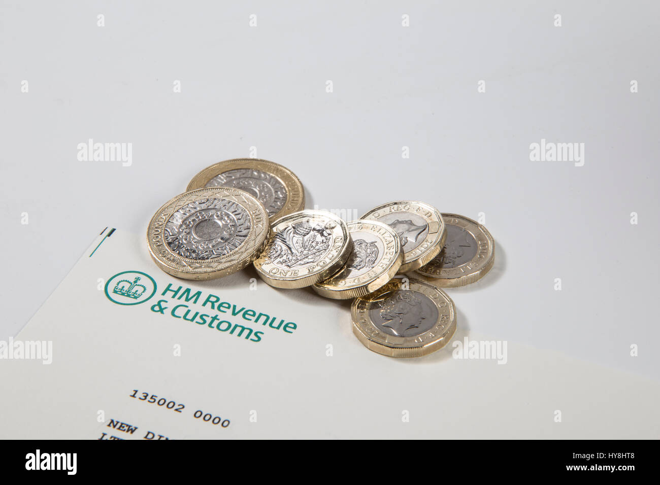 New £1 pound coins, £2 pound coins and £5 pound notes on an HM Revenues & Customs document Stock Photo