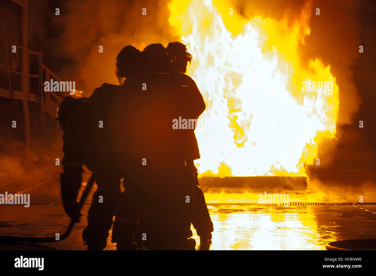 Group of firefighters in front of burning tank during firefighting exercise Stock Photo