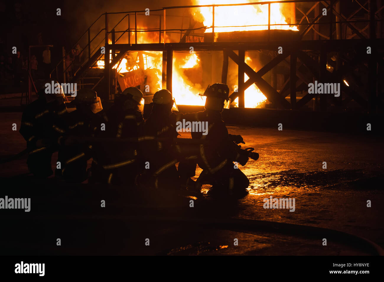 Group of firefighters kneeling in preparation to fight fire in firefighting exercise Stock Photo