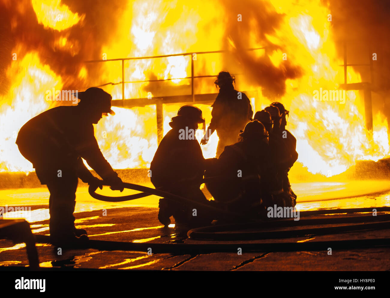 Firefighter adjusting firehose during firefighting exercise Stock Photo