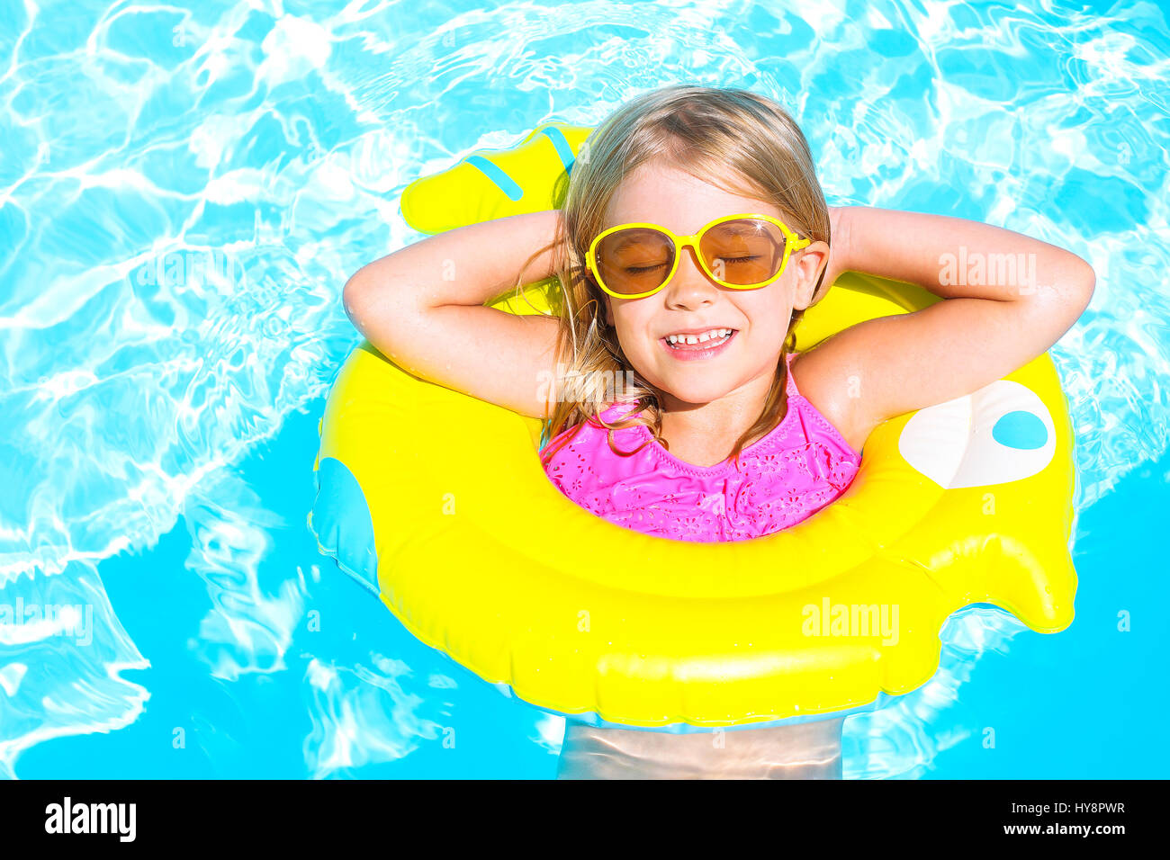 Happy funny child in swimming pool. Girl swim in a pool in an yellow