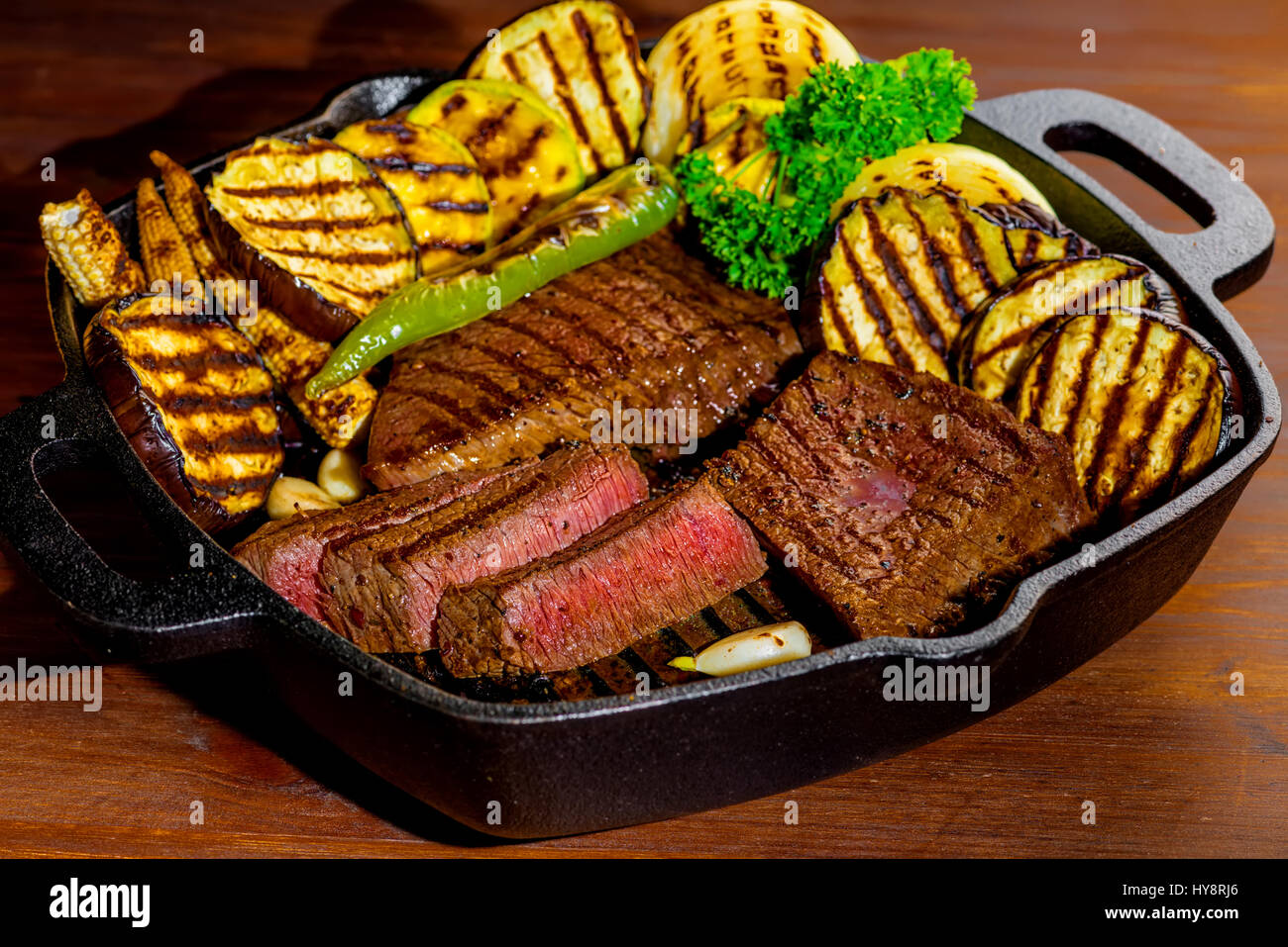 slicing tasty grilled meat with vegetable on pan, close up Stock Photo