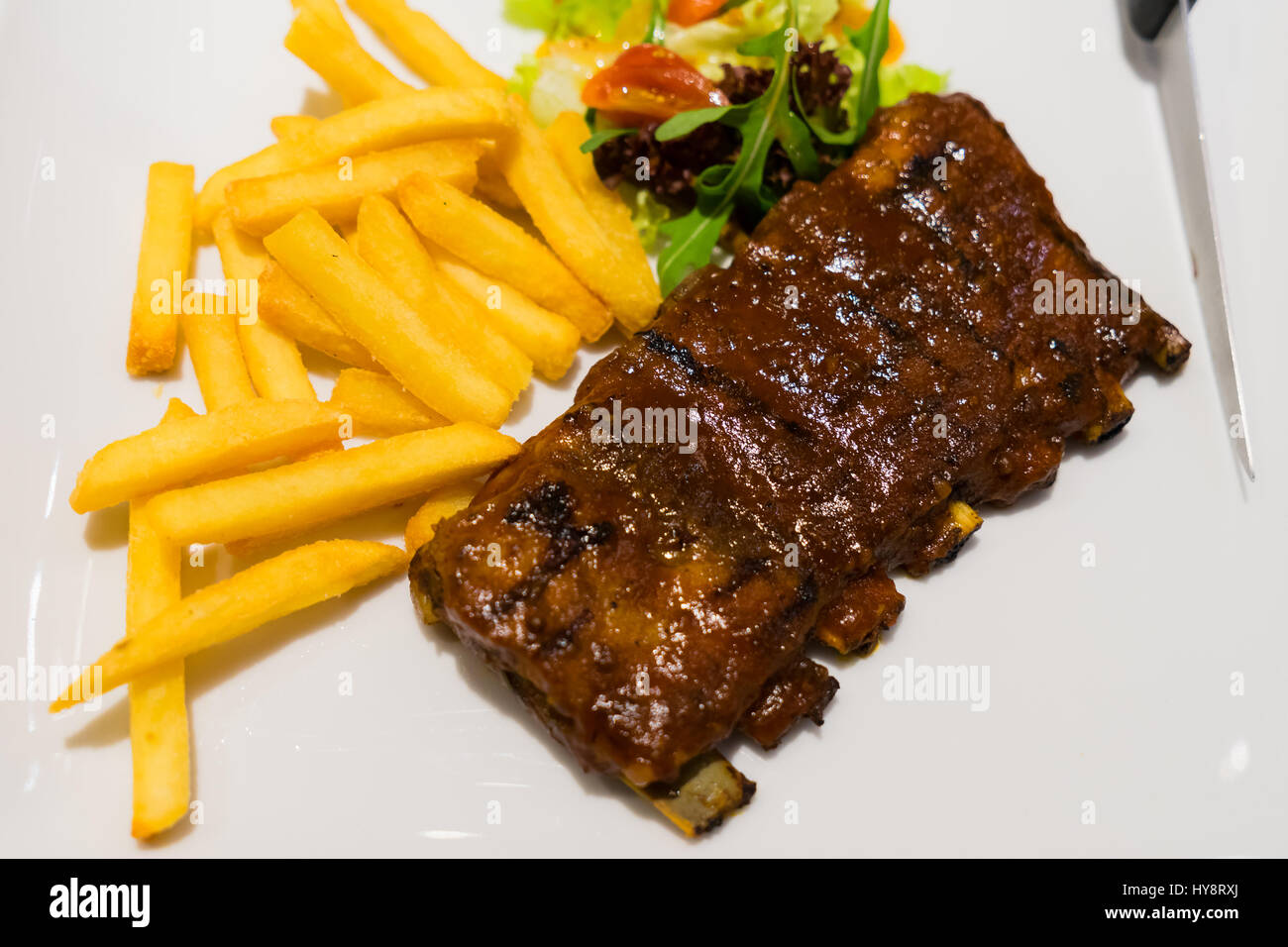 Pork ribs steak fries and vegetables on white plate, Roasted sliced