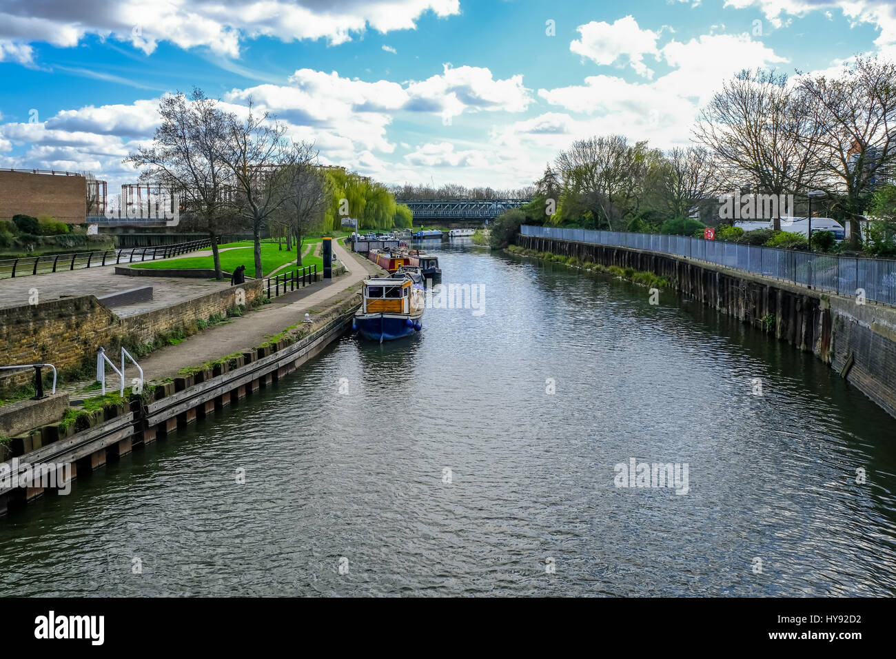 Canal, River Lee and railway bridge, shows longboats moored at the side of the water. Stock Photo