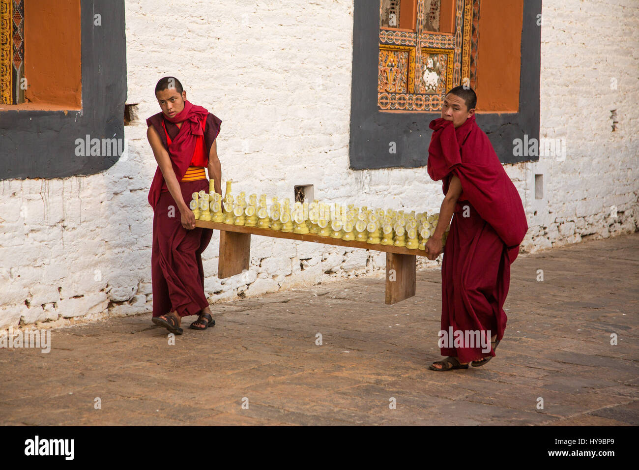 Two young Buddhist monks carrying torma or yak butter sculptures for a Bhuddist ceremony in the Punakha Dzong, Punakha, Bhutan. Stock Photo
