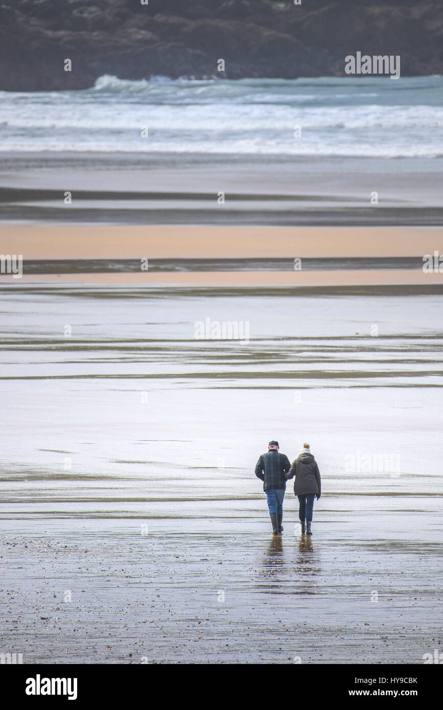 Couple People Walking Beach Shore Seaside Sea Waves Rugged Coast Coastal Low tide Exercise Exercising Fistral Cornwall Stock Photo