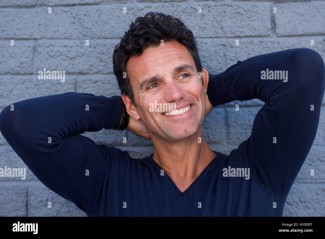 Close up portrait of a handsome mature man smiling with hand behind head Stock Photo