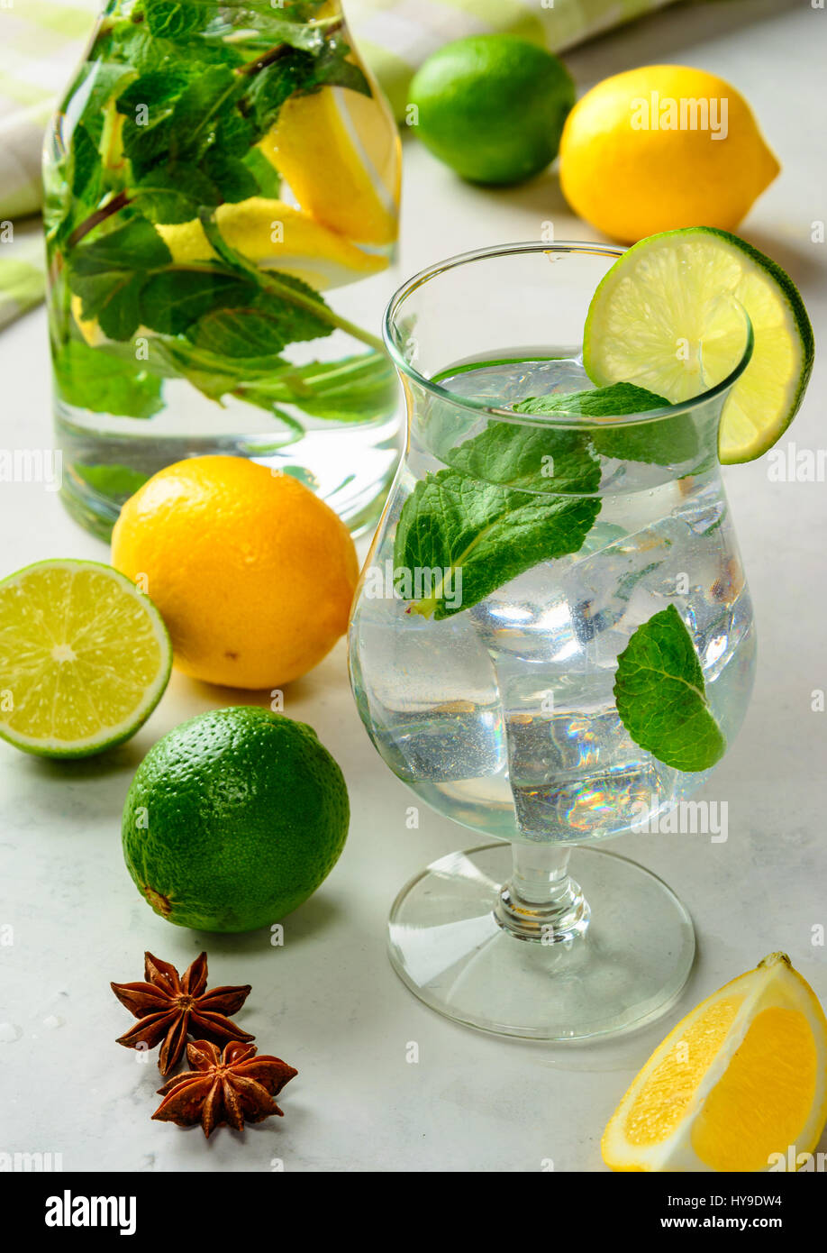 Homemade refreshing summer lemonade in a glass with lime, lemon and mint on a white concrete or stone  background. Stock Photo